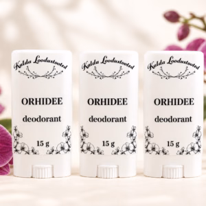 Kolm 15 g Orhidee deodoranti valges pakendis lillade orhideeõitega heledal taustal.